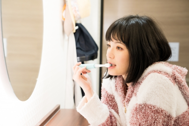 鏡を見ながら歯磨きをする女性
