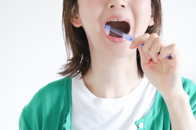 口に歯ブラシをいれる女性