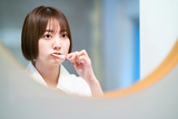 鏡を見ながら歯磨きをする女性