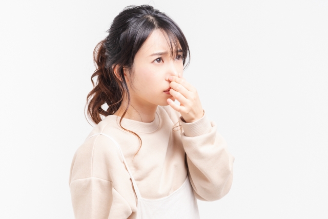鼻を抑えて悩む女性