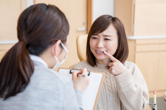 口元を指しながら病院で説明する女性