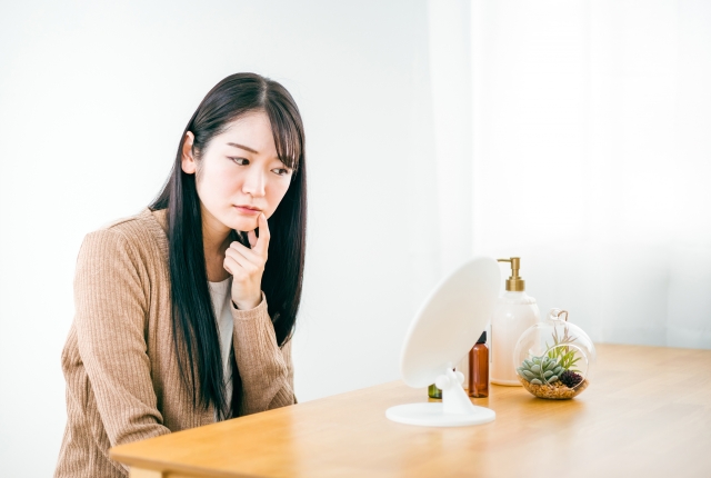 鏡で口元を確認する女性