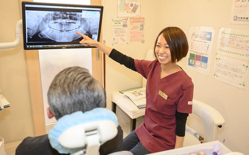 歯科衛生士が患者さまへレントゲン写真の説明をしている様子